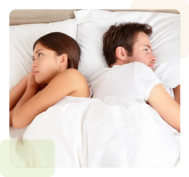 Upset young couple having marital problems or a disagreement lying side by side in bed facing in opposite directions ignoring one another.